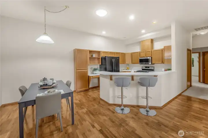 A charming open kitchen with breakfast bar seating, stainless appliances, and extensive timber floors, harmoniously connected to the spacious dining room.