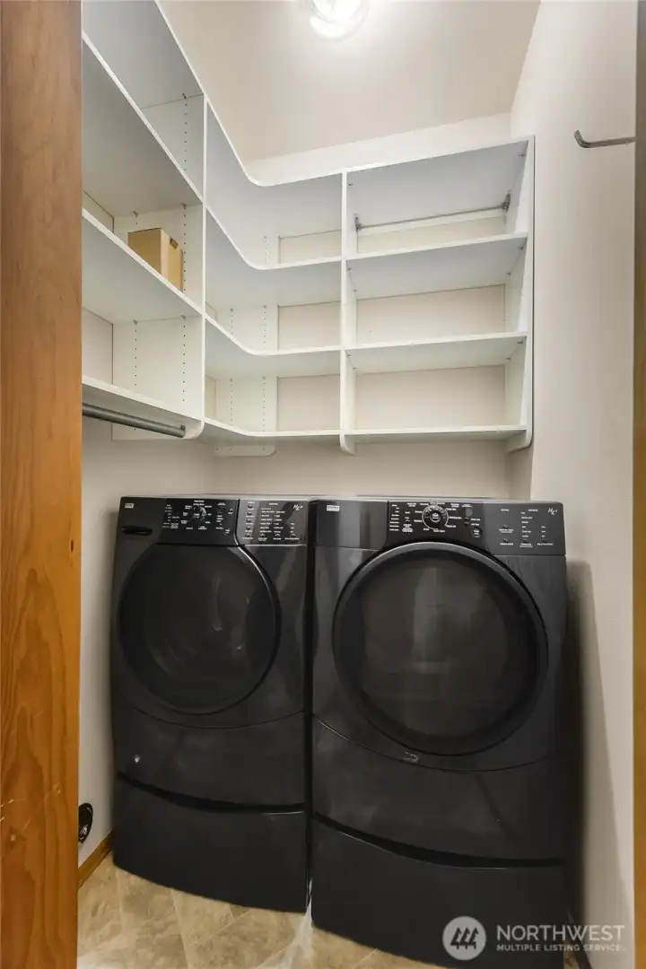 Laundry room complete with front-load appliances and built-in shelves for organization.