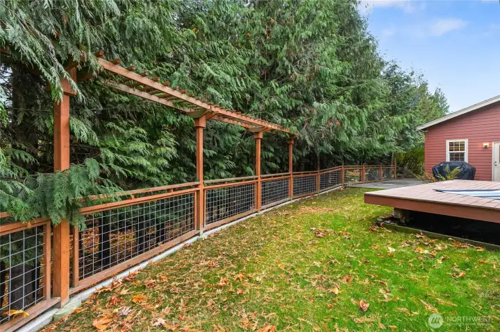 Beautiful arbor fencing surrounds the backyard and from this angle, you can see beyond the fence where a path leads down to the peaceful seasonal creek below.