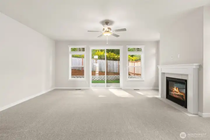 Living room with plenty of natural light featuring cozy gas fireplace with tile surround and ceiling fan. Sliding door off the living room leading to backyard patio.
