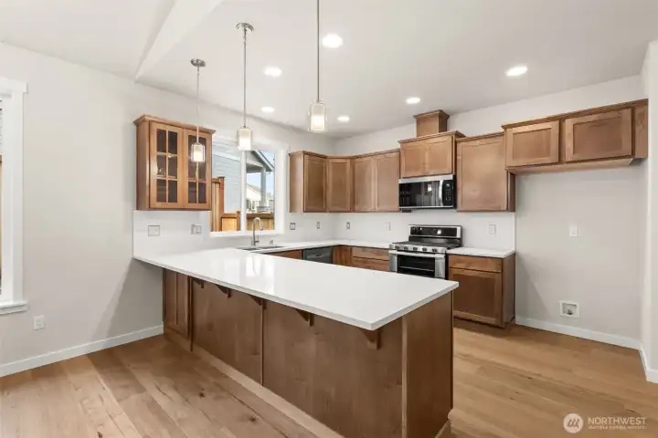Kitchen features new Toffee-stained Maple Shaker-style cabinets with quartz countertops, full tile backsplash and extended eating bar.