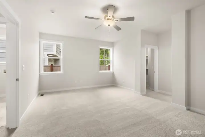 Inviting and spacious primary bedroom with ceiling fan for added comfort.