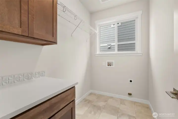 Separate laundry room with cabinets and a high hanging shelf for extended storage.