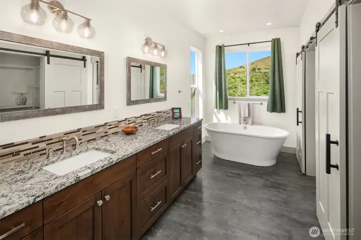 Gorgeous primary bath, dual vanity sinks, granite and tile countertops, soaking tub, walk in shower and huge walk in closet with sliding barn doors