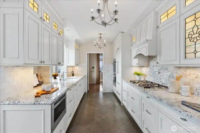 Carrera marble counter, lit custom cabinetry with leaded glass appliques, Liebherr refrigerator, Dacor gas stovetop and double ovens and Bosch dishwasher.