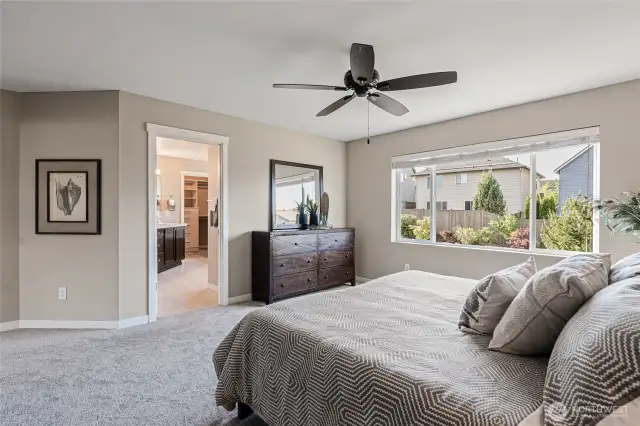 Spacious primary suite with ceiling fan, big window, walk-in closet, and en suite bathroom.