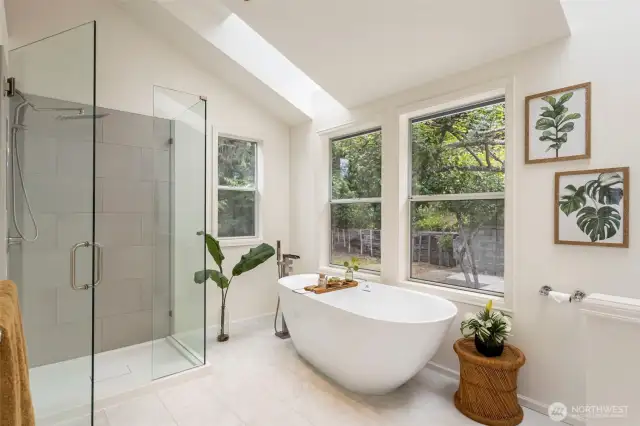 A spa-inspired bath with a freestanding soaking tub beneath a skylight invites you to unwind. Modern tilework, dual windows, and a glass walk-in shower elevate the experience.