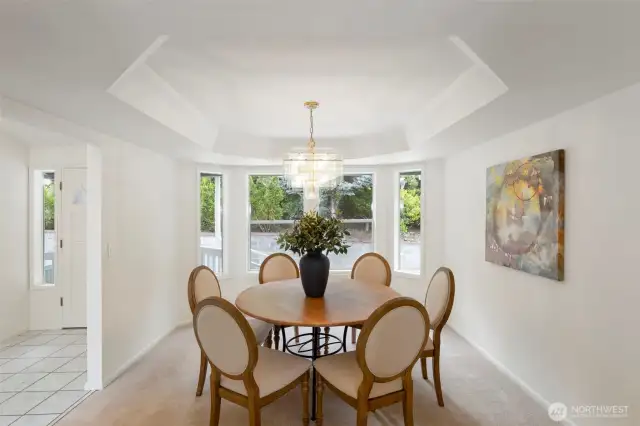 The dining area features a striking tray ceiling and surrounding windows that draw in natural light. A perfect setting for both intimate dinners and larger gatherings.