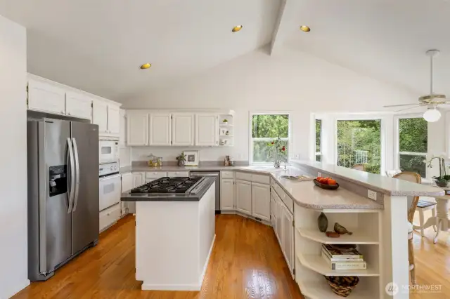 With ample counter space, gas cooking, and open shelving for display or storage, this kitchen balances form and function effortlessly. Vaulted ceilings enhance the airy feel, while warm wood floors add timeless charm.