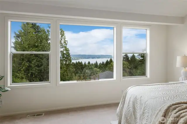 Expansive windows frame a stunning view of the Puget Sound and surrounding creating a tranquil focal point from the comfort of your primary bedroom retreat.