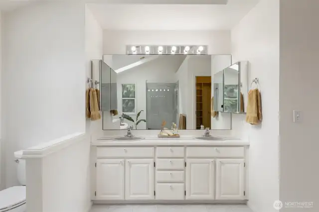 The ensuite bathroom features dual sinks, a large vanity with ample storage, and mirrors that enhance the bright and open feel of the space.
