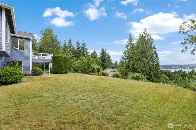 Open grassy lawn with peekaboo water views and a tree-lined horizon. Perfect for yard games, lounging, or enjoying the natural surroundings.