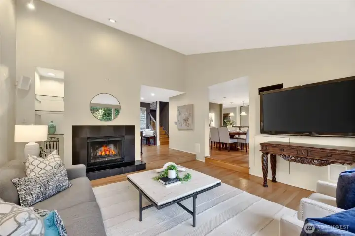 Open living space with fireplace, hardwood floors & seamless flow to dining area. Bright, inviting layout with modern touches & cozy ambiance.