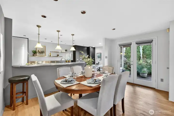 Bright dining area with hardwood floors & pendant lighting opens to updated kitchen. French doors lead to back yard patio for seamless indoor-outdoor living.