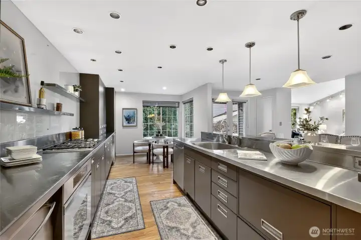 Chef’s kitchen with expansive counters, sleek cabinetry & gas range. Large island, pendant lighting & open flow create a stylish, functional space.