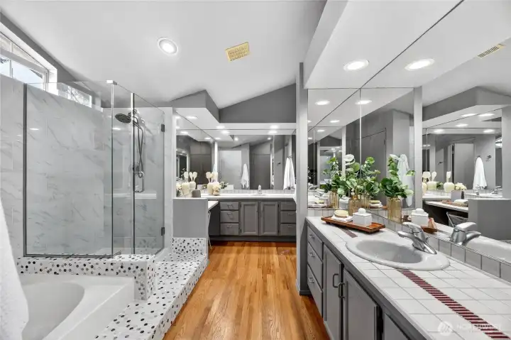 Spa-like primary bath with dual vanities, soaking tub & glass shower. Spacious layout, tile finishes & great lighting create a relaxing retreat.