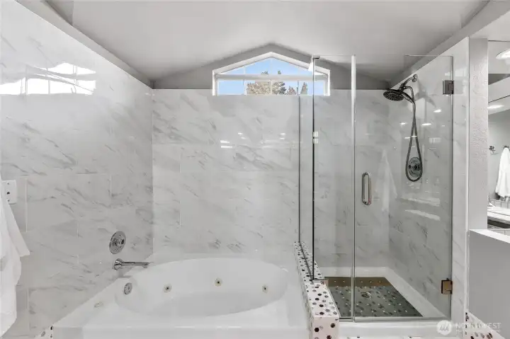 Luxurious bath with soaking tub & glass-enclosed shower. Elegant tilework, natural light & spacious design create a relaxing, spa-like experience.