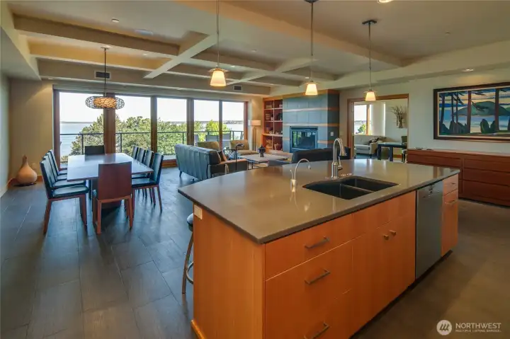Looking from the kitchen across the island toward the dining area and living room with the family room/office beyond.