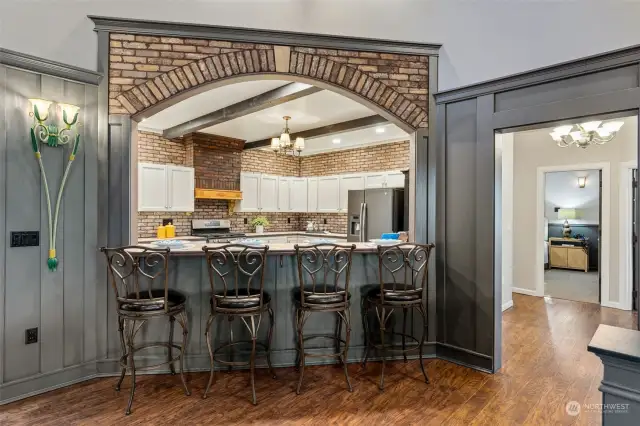 Brickwork that matches the fireplace frames the breakfast/buffet bar with a graceful arch that brings the kitchen into focus. A wonderful place to connect the kitchen with the main living area.