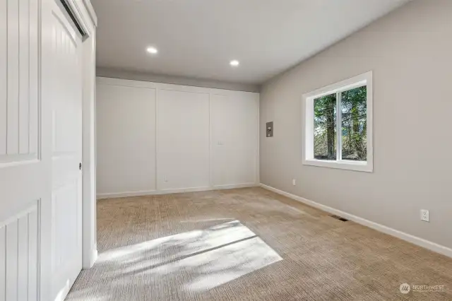 The 3rd bedroom is bright and light with a large wainscot white accent wall and plush carpeting, all with a wonderful wooded window view.