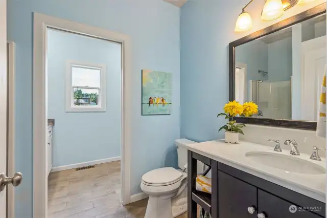 On the main floor, you’ll find a ¾ bathroom complete with shower, vanity shelf and cabinet with undermount sink, all next to the convenient laundry room through the doorway.  There is plenty of space to spread out in this laundry room, with easy-care tile floors, tons of cabinetry and a long folding counter next to a sun-filled window!