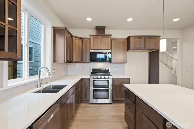 Cocoa-stained maple cabinets and quartz countertops throughout home. Double ovens are included too!