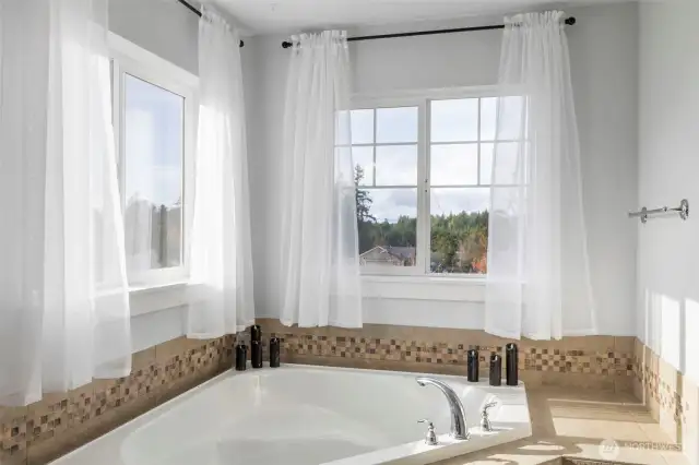 Oversized soaking tub with designer tile surround accents.