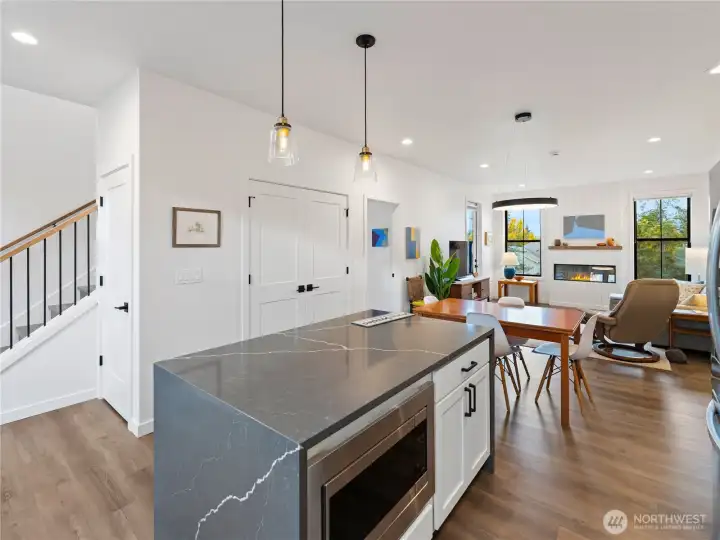 Waterfall island with built in microwave and storage on one side, seating on the other.