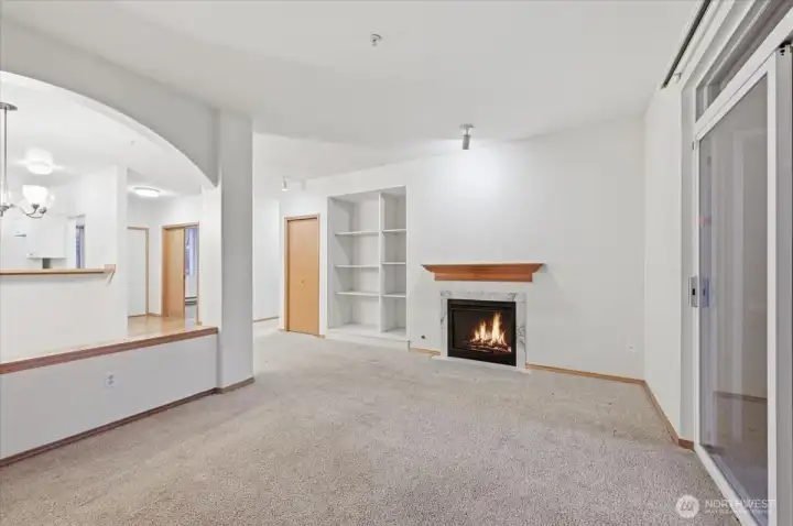 Living room with gas fireplace. Open to dining and kitchen area.