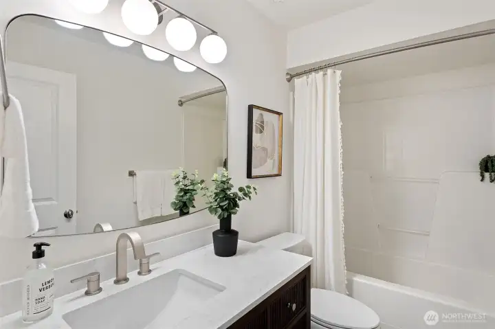 Newly remodeled lower level bathroom features new Marmoleum flooring, new vanity, mirror, faucet, light fixture and new Kohler toilet.