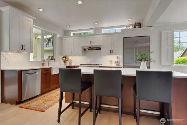 Two tone cabinetry is complemented by white quartz countertops and a sleek custom tiled backsplash.