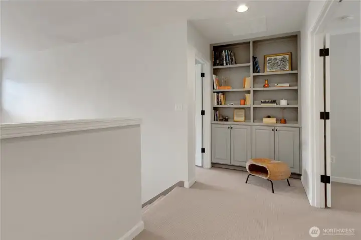 At the top of the staircase, the upper landing opens up to built-in bookcases blending function and style for a cohesive look.