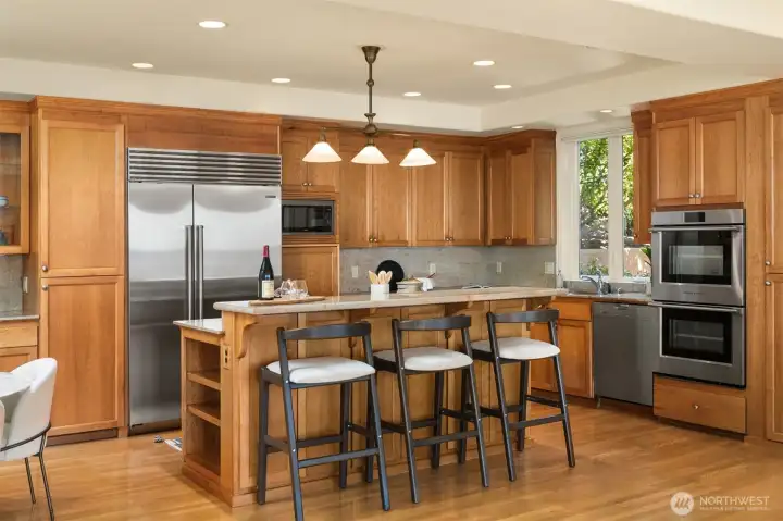 Warm caramel wood cabinetry with ample storage and slab granite countertops.