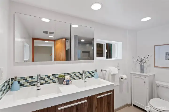 A beautifully designed lower level bathroom with dual sinks and a spa-style shower featuring multiple heads. A beautifully designed lower level bathroom with dual sinks and a spa-style shower featuring multiple heads.