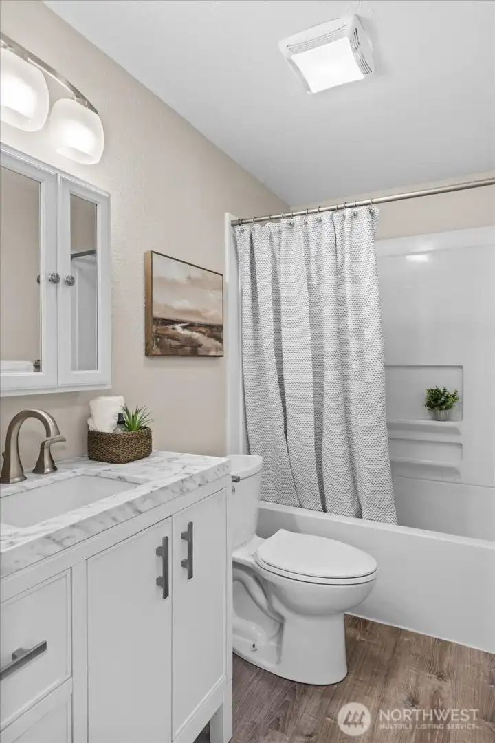 Fully updated hall bath off the kitchen/dining offers thoughtful updates such as new shower insert, vanity and lighting.