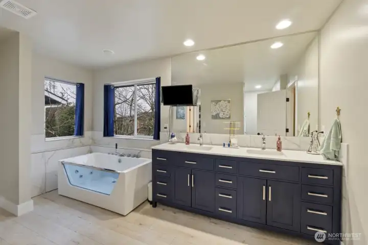 Primary Ensuite Bathroom with double vanity, quartz countertops and jetted soaking tub with various colored lighting!