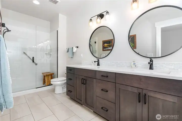 The primary bathroom boasts tile floors, a double-sink vanity, and a walk-in shower for both style and functionality.