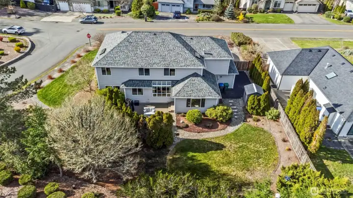 Backyard with partial fencing, trees and shrubs for privacy.