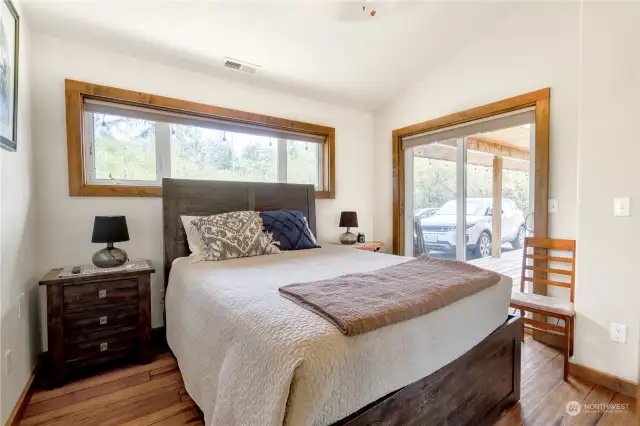 Downstairs (guest) bedroom with its beautified, original hardwood flooring and Slider glass doors out to the covered decking. Custom hardwood trim throughout.