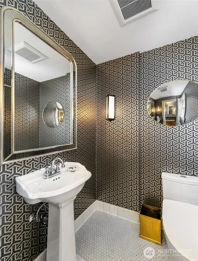 The Powder Room glimmers with quiet drama—its metallic wallcovering, faceted mirror, and sculptural lighting a nod to the mansion’s Art Deco revival. A petite but polished moment of luxury, seamlessly woven into the home’s elegant main floor flow.