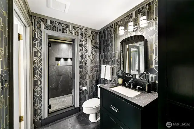 The En Suite Bath for Suite 2 makes a bold statement in House of Hackney’s richly patterned wallpaper—a nod to British maximalism. Paired with arched mirrors, matte black finishes, and a spacious walk-in shower, the space channels vintage glamour with confident, contemporary edge.