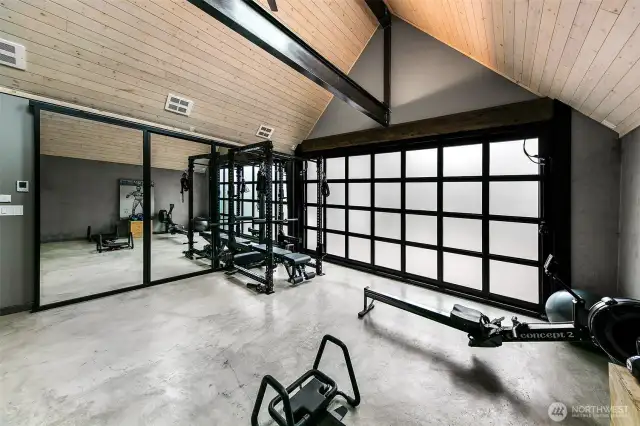 This 330-square-foot space serves as both Home Gym and Garage, seamlessly blending form and function. With mirrored walls, vaulted ceilings, and designer lighting, it inspires peak performance—while the sleek, trackless glass door preserves its original utility for secure vehicle storage.