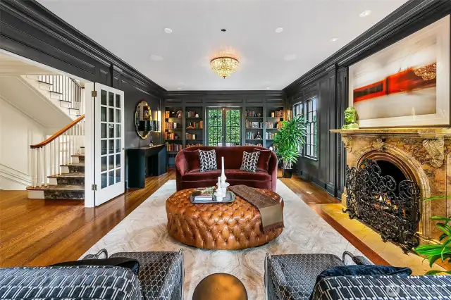 Wrapped in moody blue and anchored by a carved marble fireplace, the Living room invites conversation beneath a canopy of Italian crystal. Ornate millwork, now fully enveloped in paint, frames a space where Old World craftsmanship meets Art Deco allure.