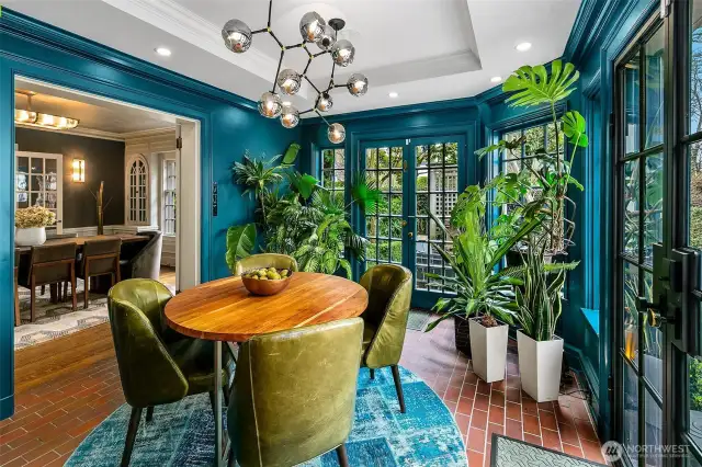 A jewel-box Solarium, drenched in jewel-toned teal and kissed by natural light. With its brick floor, verdant outlook, and sculptural chandelier, this intimate indoor garden blurs the line between home and haven—ideal for morning coffee, creative musings, or spirited conversation after dark.