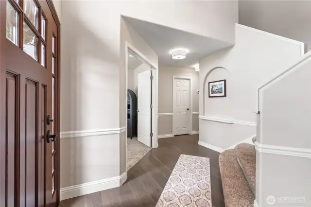 Custom front door leads into the foyer featuring the new flooring and peaceful color scheme