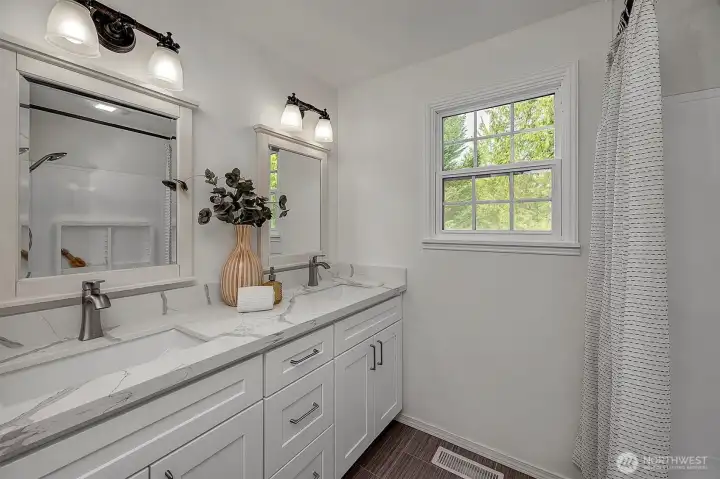 The updated bathroom offers white shaker cabinetry, quartz countertops & new floors.