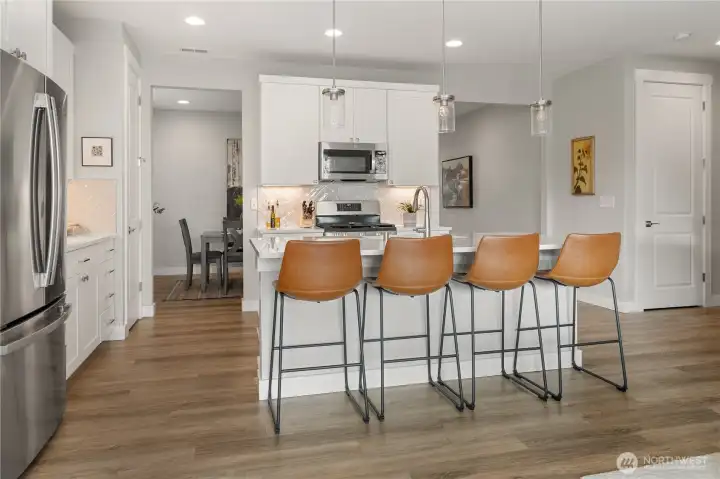 Spacious Kitchen with Island Seating – Bright white cabinetry, quartz countertops, and pendant lighting create a stylish backdrop, while the large island with bar seating connects seamlessly to the dining area.