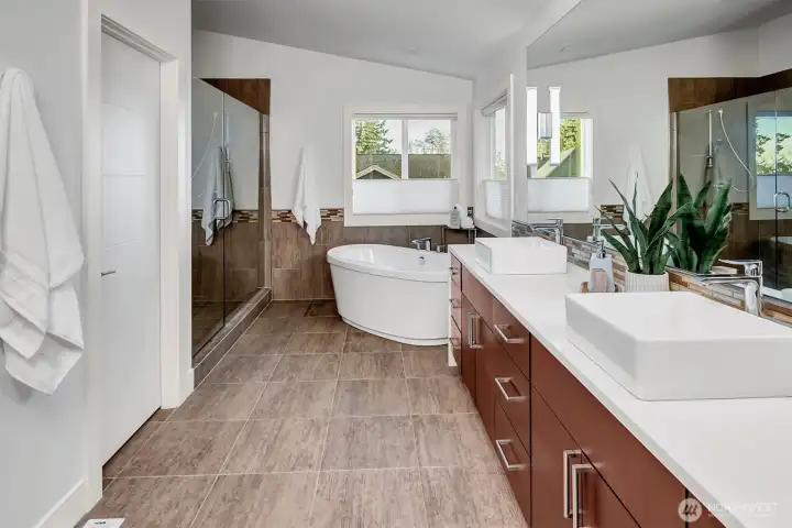 The spa-like bathroom features a standalone soaking tub, generous walk-in shower, & skylight.