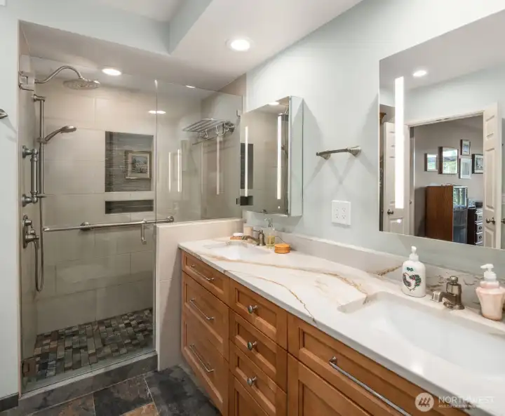 Spa-like bath features Robern medicine cabinets each with LED lights and a magnetic bar to hold small tools; slab quartz counters with dual undermount sinks; grab bars plus in-shower towel rack; dual shower heads including a rain shower and a hand-held, adjustable-height wand; built-in bench seat; and, lighting upgrades including floor-level night lights.