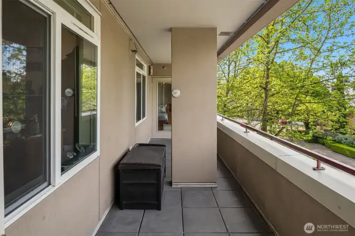 North-facing covered deck has access from living area and primary bedroom.  It looks out to library, pools, Kirkland Performing Arts Center and Kirkland Urban.